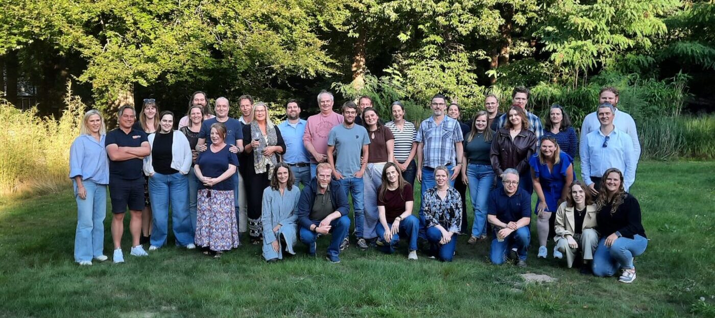 Groepsfoto van medewerkers en partners bij de viering van het 25 jarig bestaan.